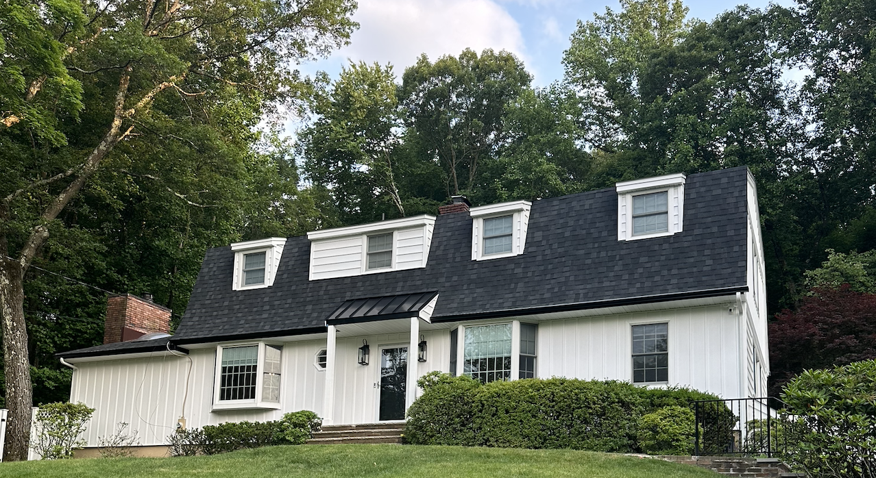 After — Cape Cod with new black architectural roof and white board & batten siding